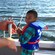 Um homem segurando um peixe ao lado de um jovem garoto pescando ao lado de um barco